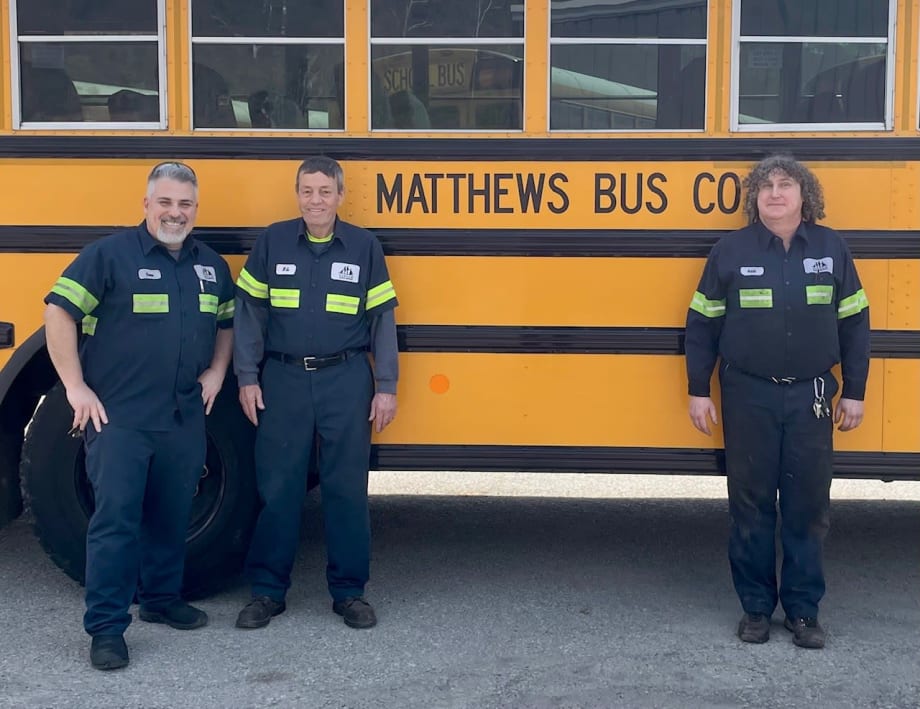Matthews Bus Company maintenance team members stand in front of a yellow school bus, recognized by Pennsylvania State Police for fleet safety, cleanliness, and inspection performance.