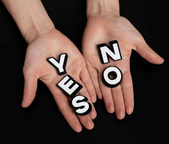 Image of two human hands, one holding the word yes, the other the word no
