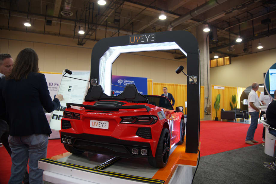 A red sports car sits underneath and AI-driven damage detection scanner.