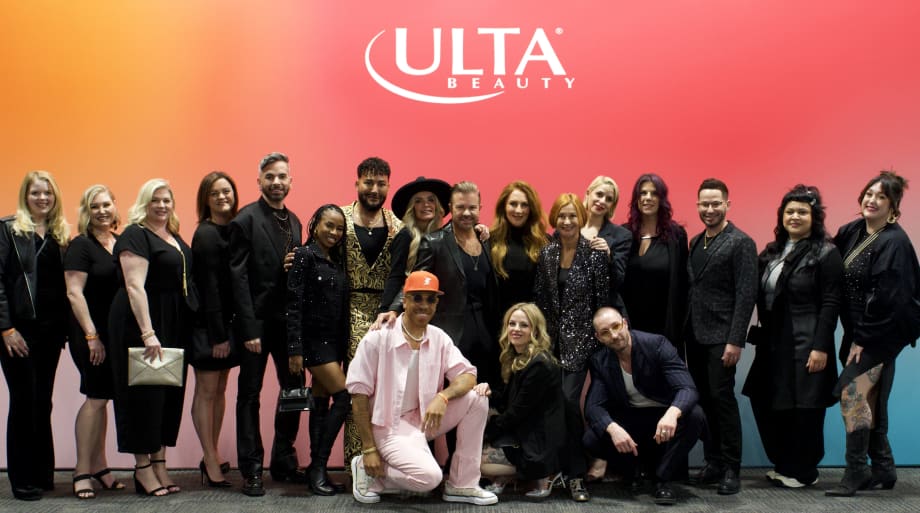 A smiling group of people, most dressed in black, in front of an Ulta sign.