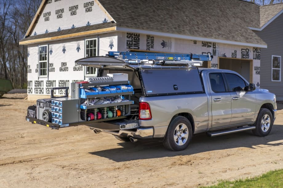 An upfitted truck with ladder rack and storage on a construction site.