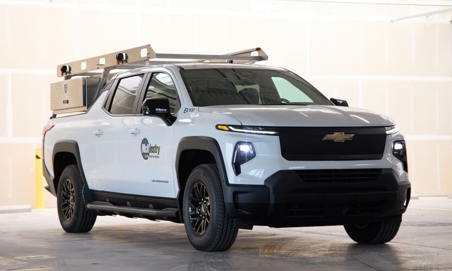 A full photo of a Silverado electric pickup rests in a stone garage with the McKinstry logo on its left side.
