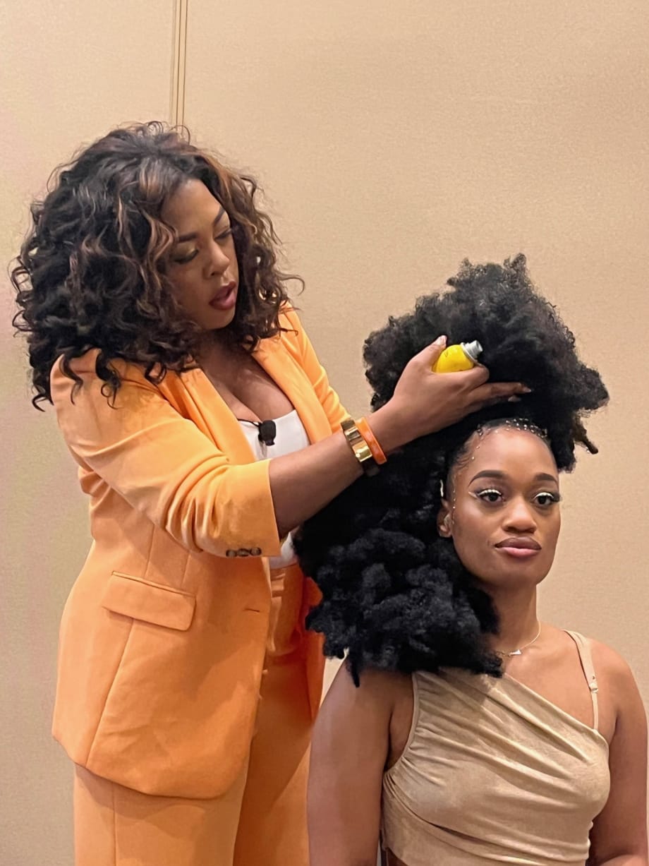 A hairstylist works on a model's hair.