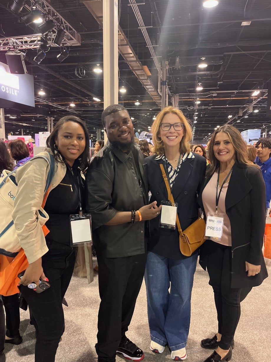 A group of four people stand and smile for a photo.