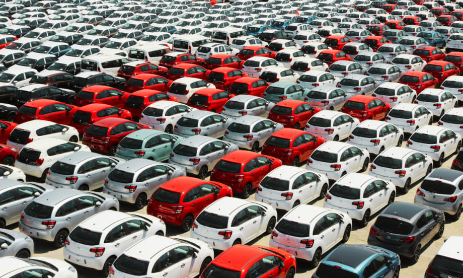 A car lot filled with red, gray, and white cars.