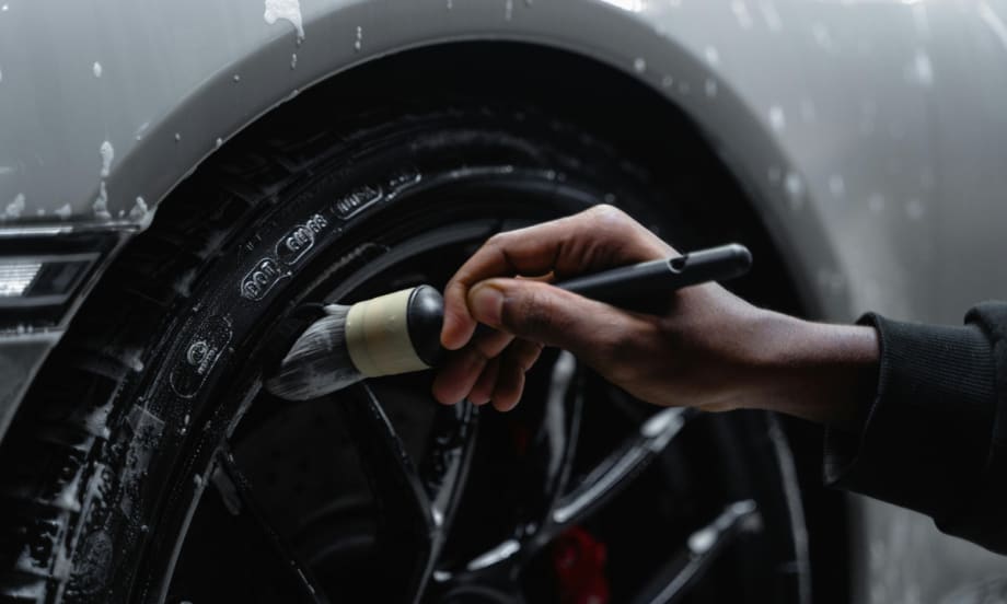 Close up shot of someone cleaning the crevices in a hub cap and tire.