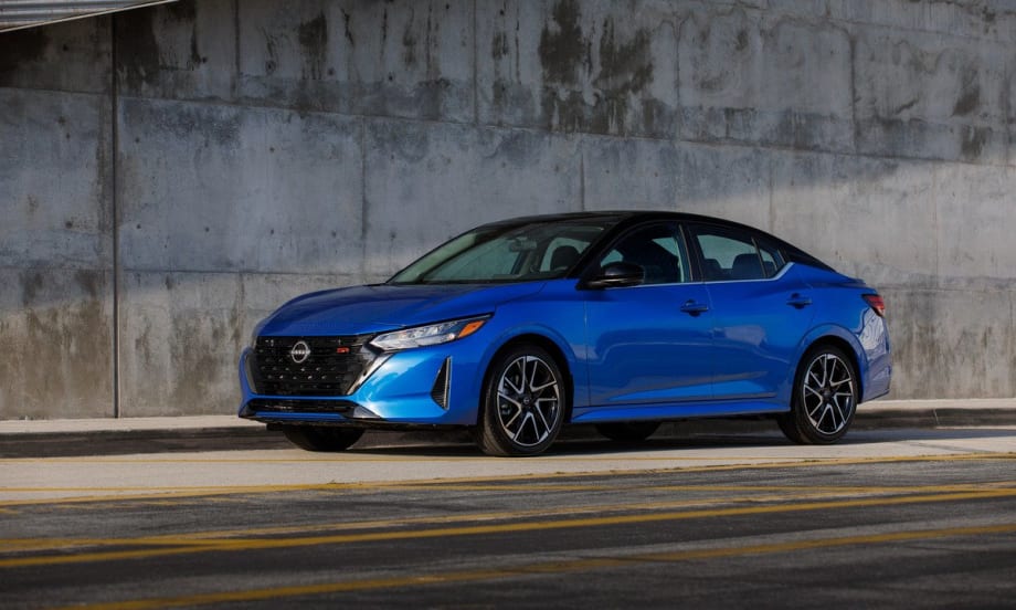 A cobalt blue 2025 Nissan Sentra parked on the side of the road underneath an overpass.