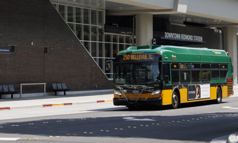 A green and yellow King County Metro bus outside a station.
