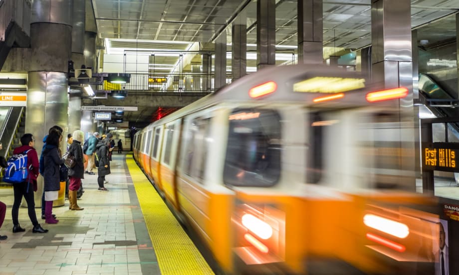 An MBTA Orange Line passenger train driving through a station.