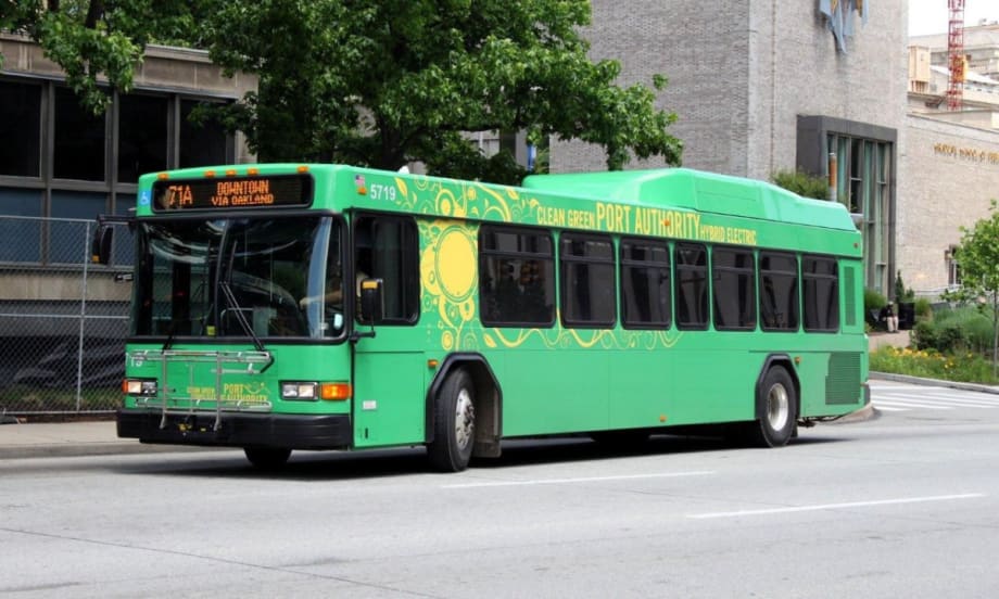 A bright green PRT bus on a city street.