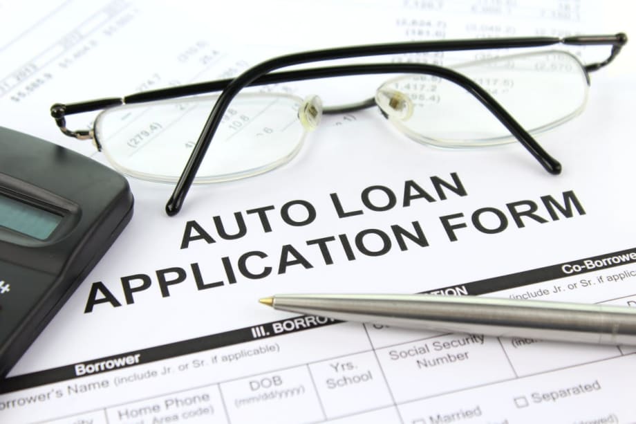 Photo of auto loan application form with eyeglasses, pen and calculator on top of it