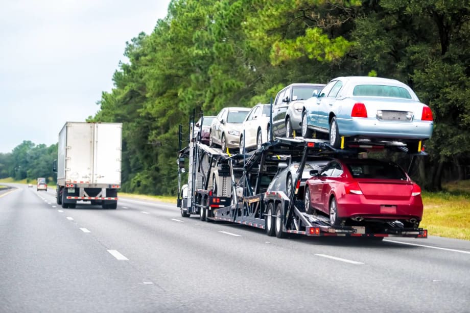 A double-decker stinger auto transporter driving down the freeway.