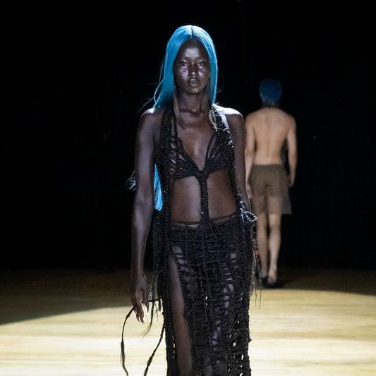 a fashion model with blue hair walking down a runway