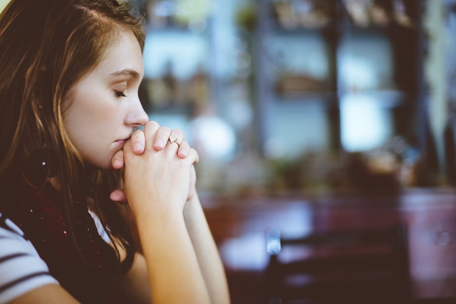 A woman with her eyes closed and hands clasped