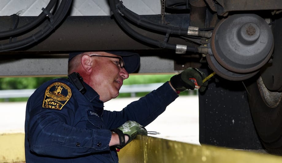 CVSA inspector looking at brakes underneath truck