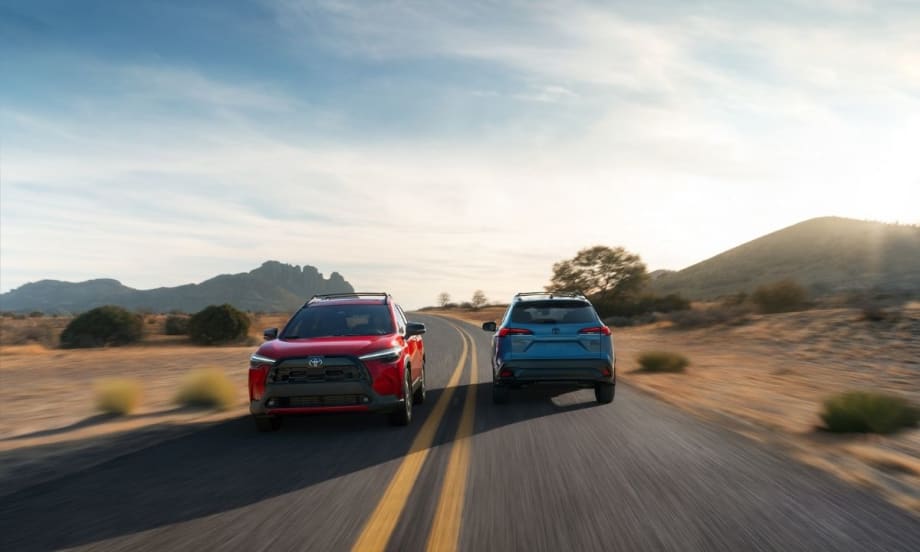 Both new Toyota Corolla Cross models driving on a road.