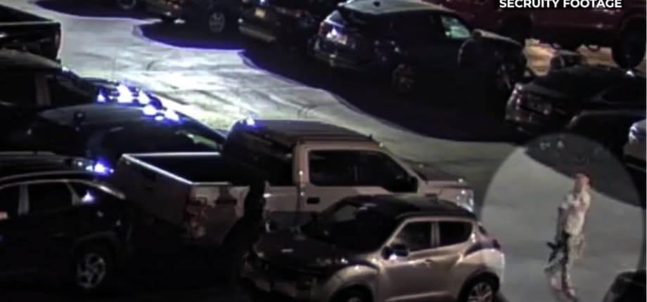 Night security footage of parking lot with multiple vehicles and blue emergency lights
