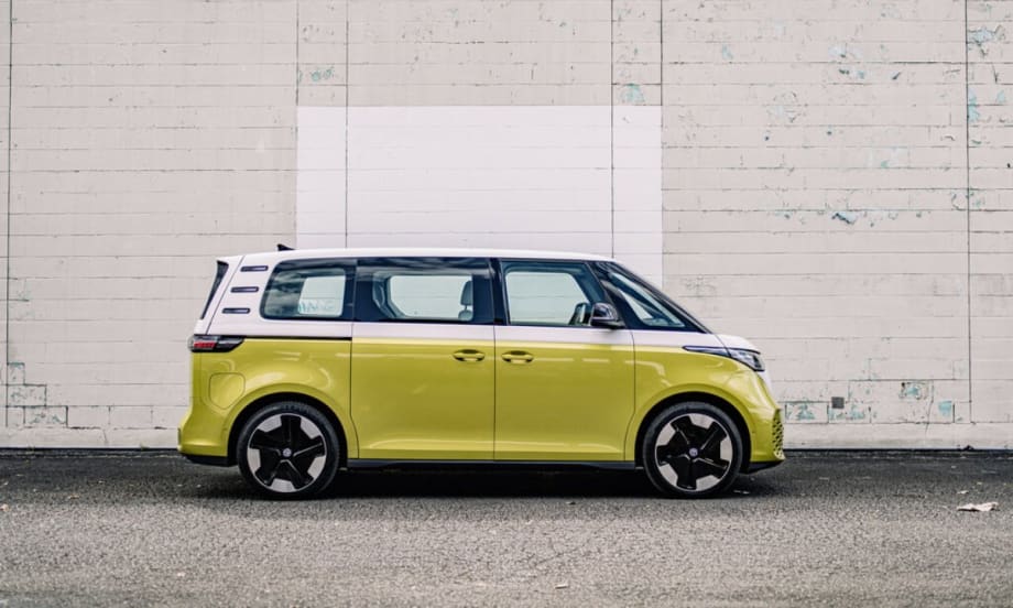 An electric green Volkswagen ID. Buzz parked in front of a white brick wall.