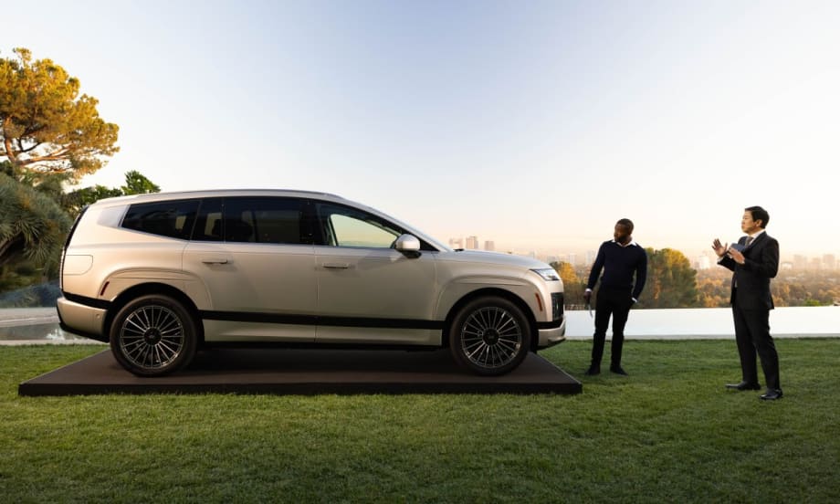 An image of a new Hyundai Ioniq 9 parked on a green lawn with two business men standing off to the right.