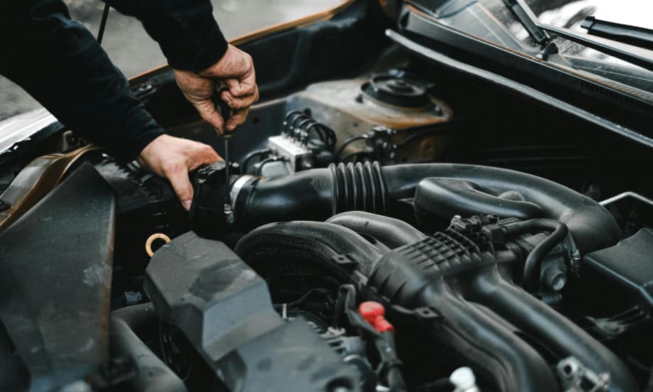 The hands of an auto mechanic checking the engine of a car.