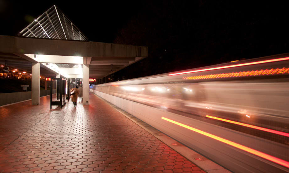 Light trails of a passenger train passing by a station at night.