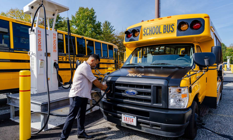 A man connecting a Zenobē charger to a school bus.