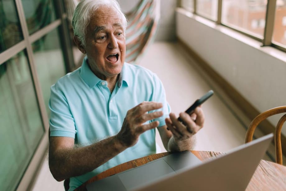 A thrilled older gentleman sees a valued used vehicle for sale on a digital device.