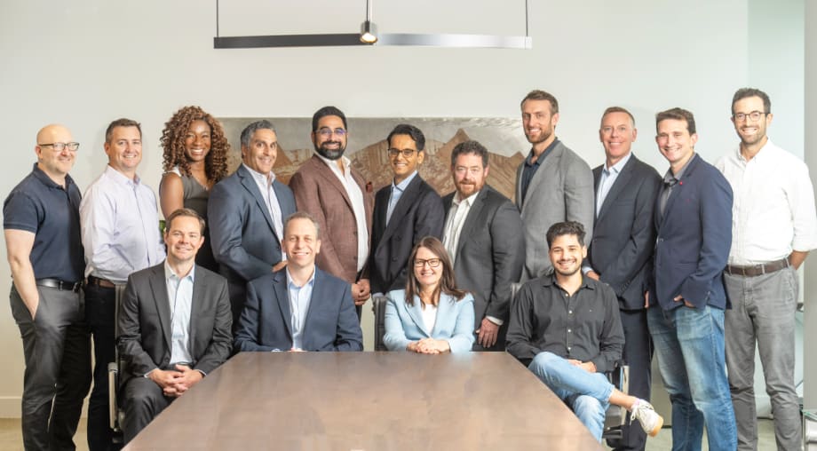 Executives pose around boardroom table.