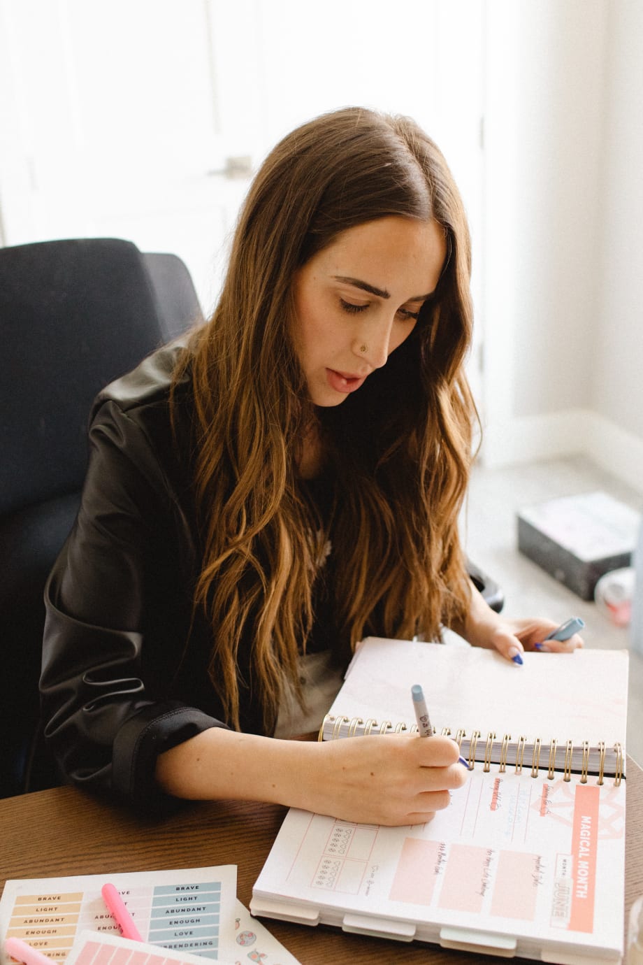 A woman seated at a desk, writing in a calendar.