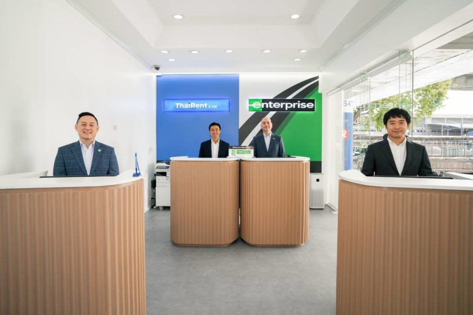 Representatives of Thai Rent-A-Car stand at airport service counters.