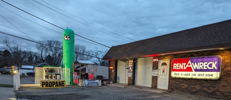 Inflatable green pop-up tank next to car rental outlet.