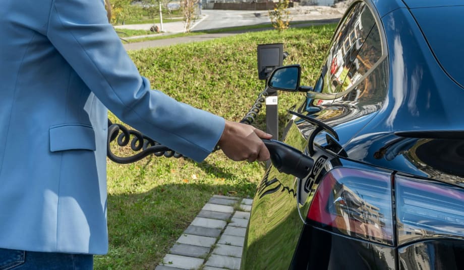 person outside plugging in electric vehicle to charge