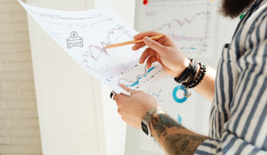 man holding up sales report and pointing with pencil
