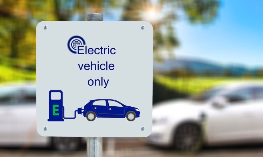 Image of a sign that says "Electric Vehicle Only" in front of charging vehicles.