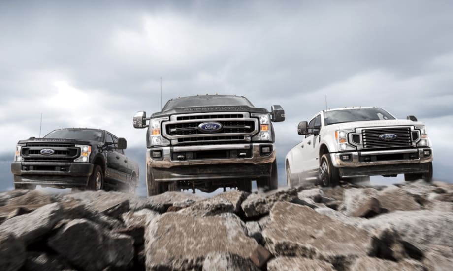 Various 2021-2022 Ford Super Duty driving on rocks towards the camera.