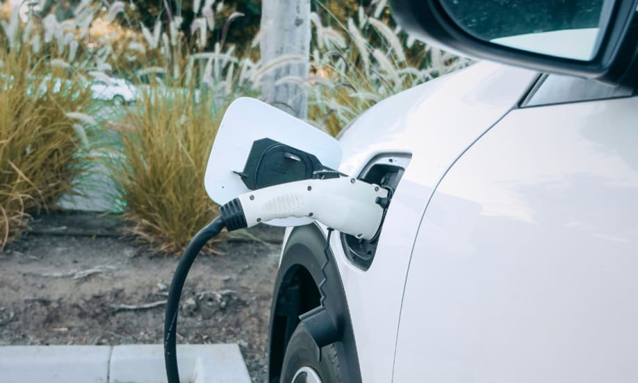 A white passenger car being fueled via electric charging.