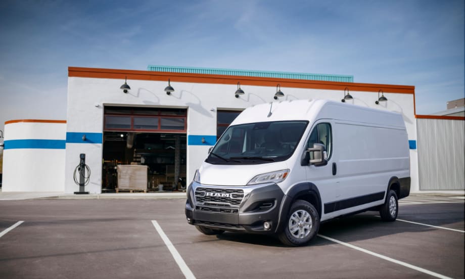 Front left side of a 2025 Ram ProMaster EV parked in front of a auto shop.