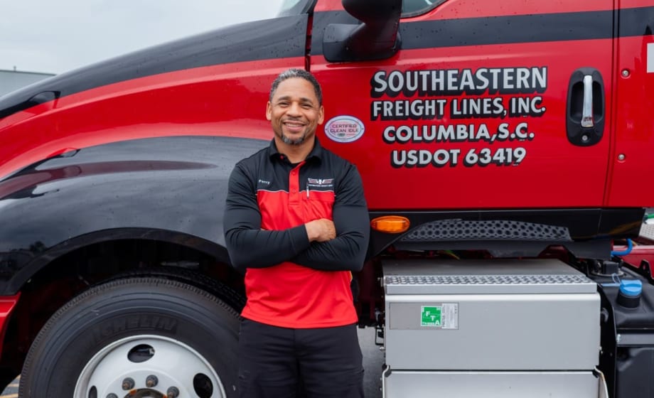 Photo of smiling truck driver Harold Perry with arms crossed in front of Southeastern Freight Lines truck