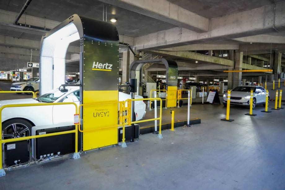 A vehicle inspection arch-style imaging structure that takes photos of rental cars returning to an airport parking deck.