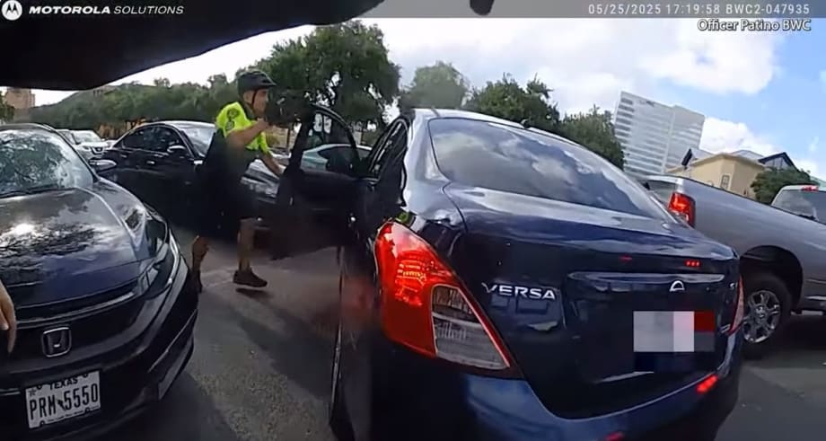 Dashcam view of traffic stop with police officer near dark blue Nissan Versa