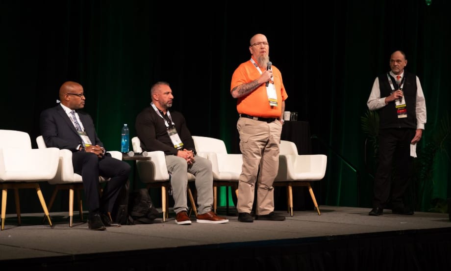 Panelists seated and standing on stage at conference.