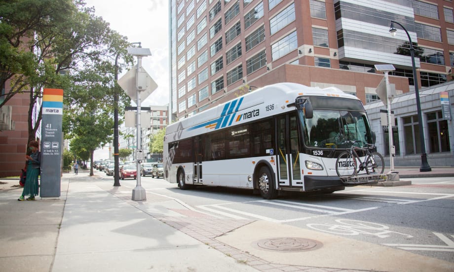 A white MARTA public transit bus near a bus stop.