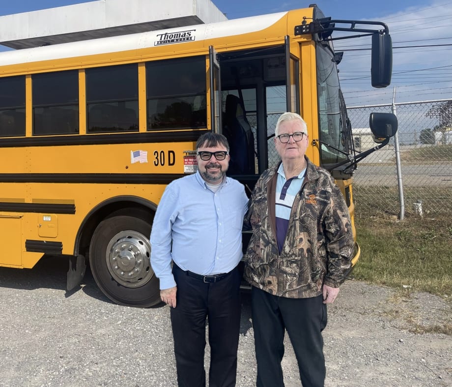 two men stand in front of a school bus in tennessee