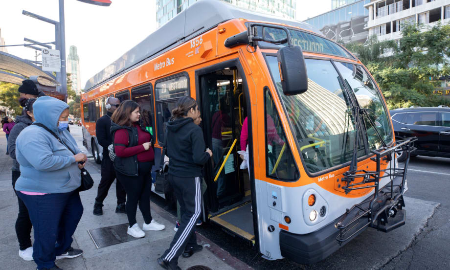Riders board an orange and gray LA Metro bus.