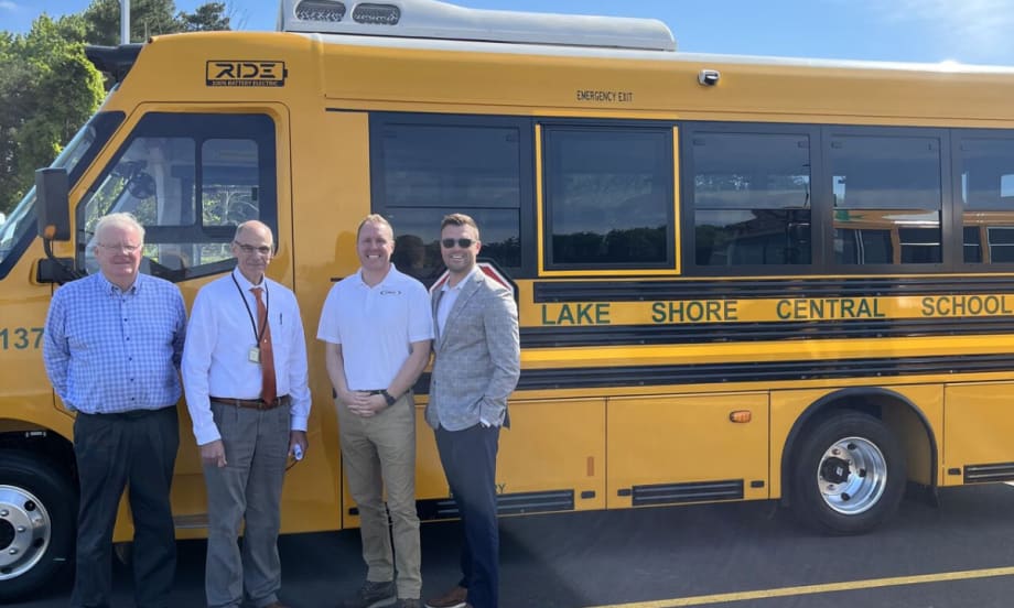 District official posing with a RIDE electric school bus.