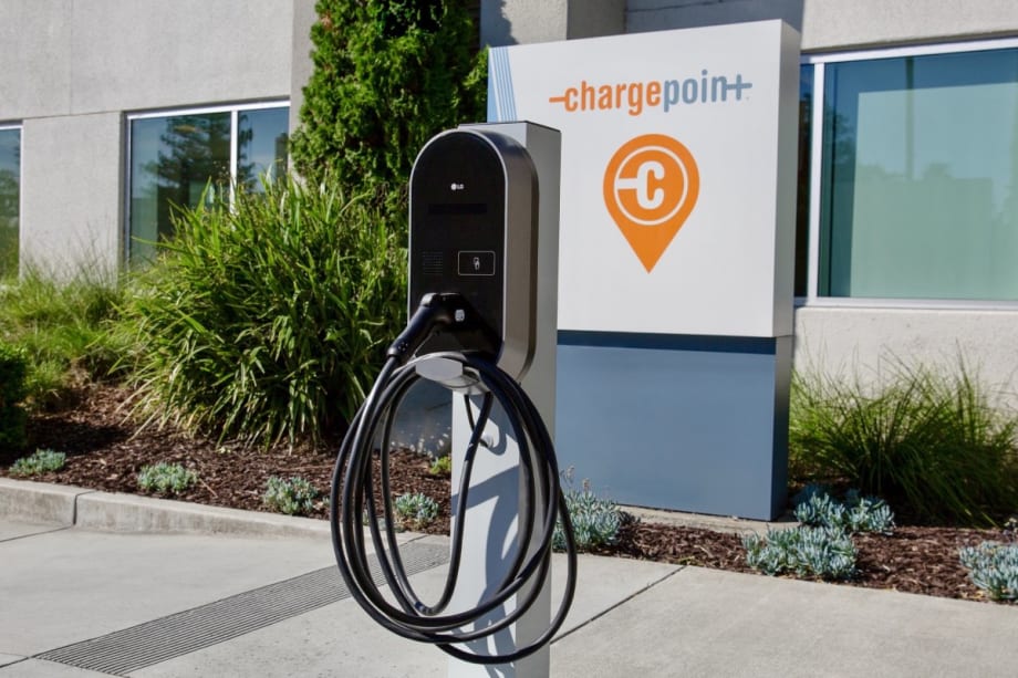 An outdoor LG electric vehicle charging station in front of a ChargePoint company sign and office building.