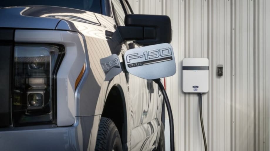Light gray Ford F-150 truck with charging port open and charger connected.