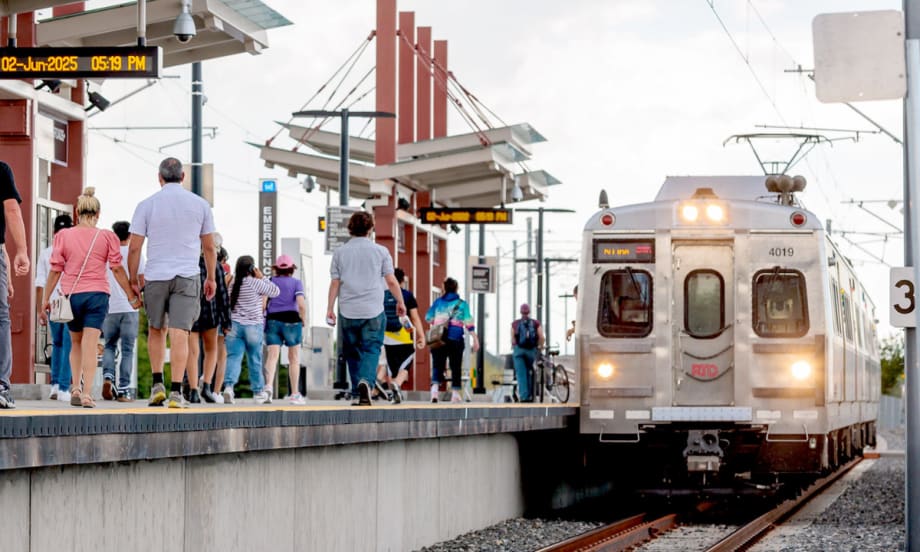 Riders walk down an outdoor rail line platform for the Regional Transportation District in Denver, Colorado.