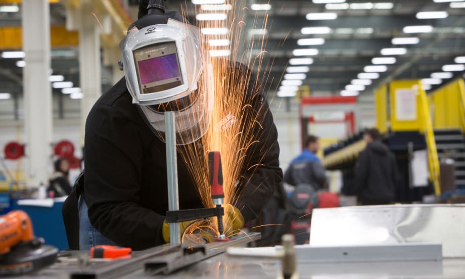 A worker cutting metal.