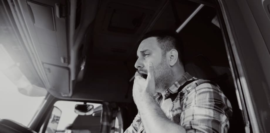 Truck driver yawning behind wheel